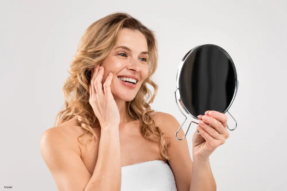 Woman touching her face looking in the mirror.
